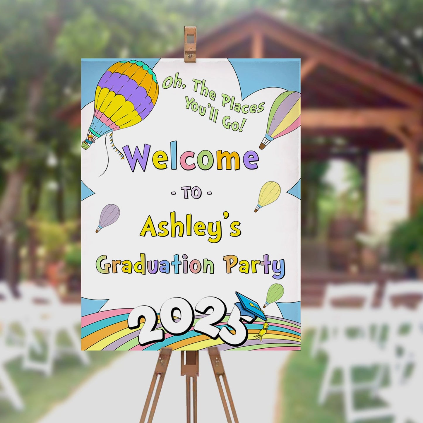Graduation party sign with colorful balloons on an easel outdoors.