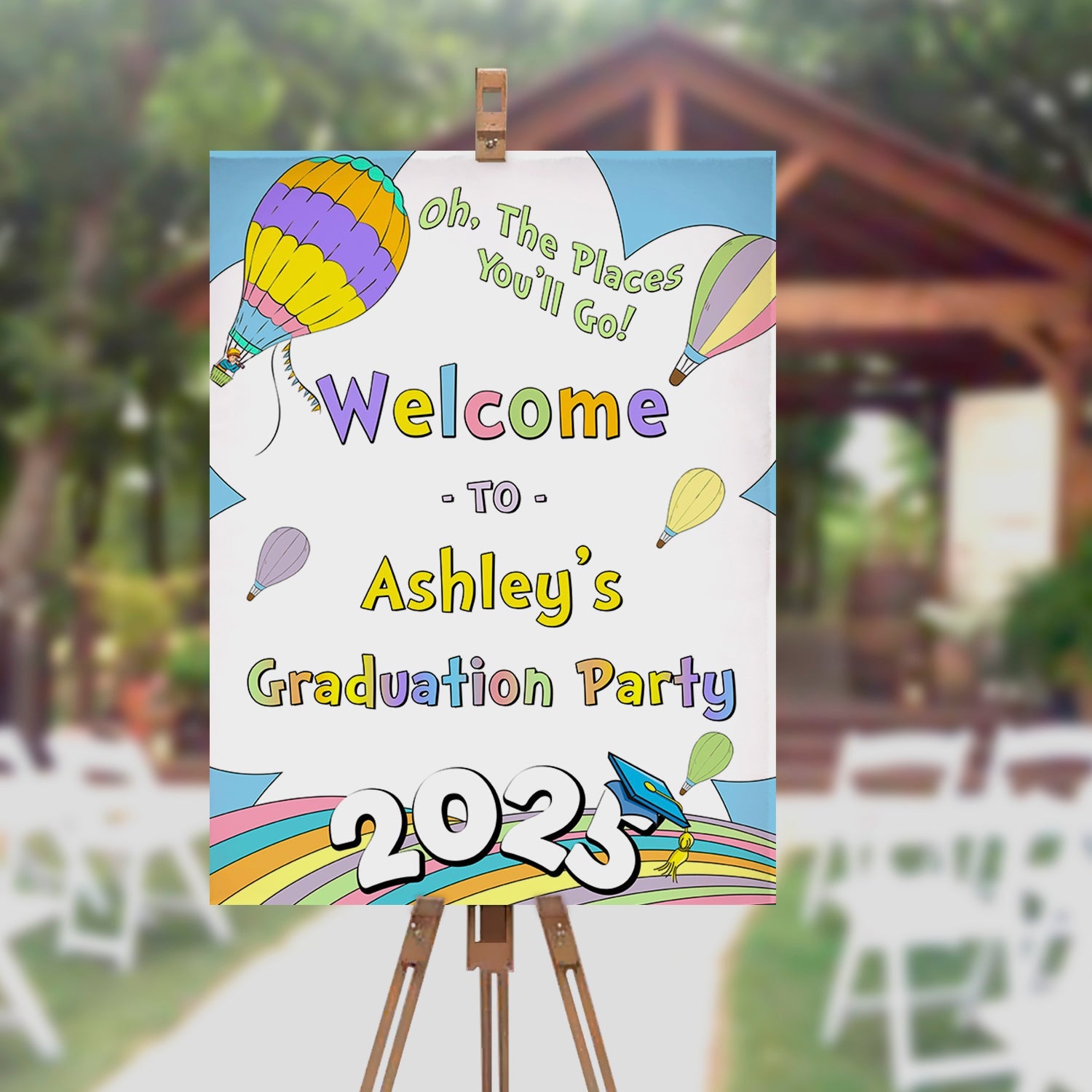 Graduation party sign with colorful balloons on an easel outdoors.
